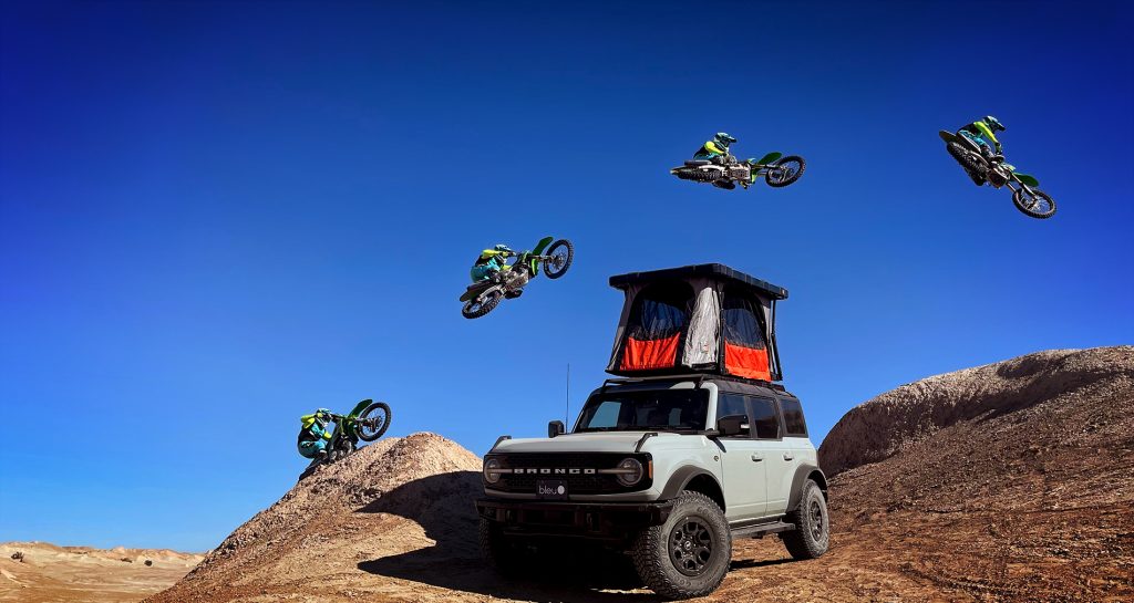 Motorcycle jumps roof top tent in desert